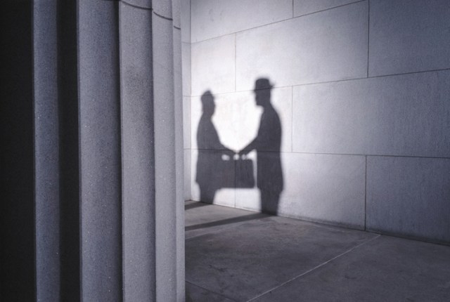 Shadows of two men with briefcase shaking hands, side view